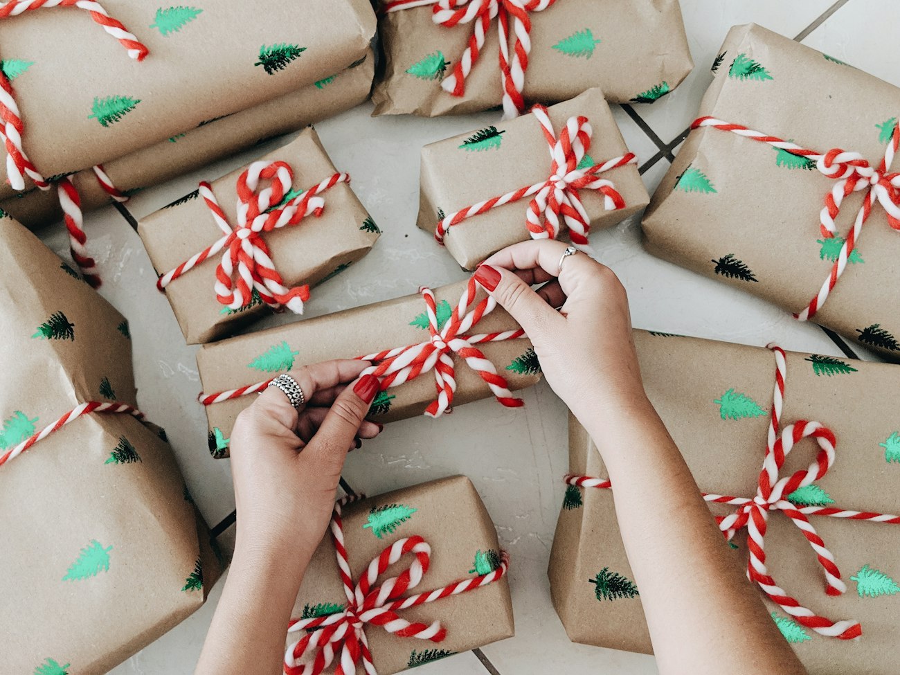 Hands wrapping a row of gifts by hand