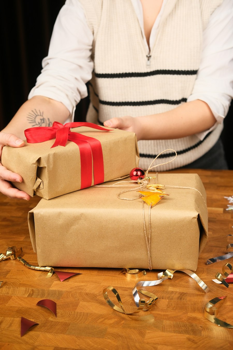 Hands wrapping gifts in brown paper and ribbon